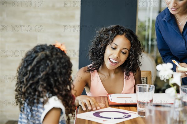 Mother and daughter reading menu restaurant table