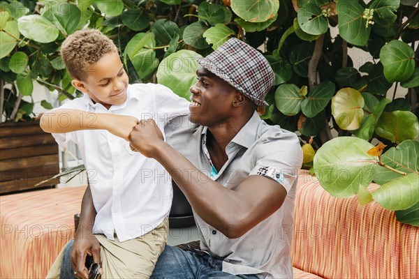 Father and son giving fist bump in backyard