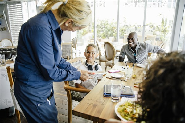 Server bringing food for family in restaurant