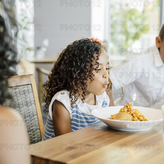 Girl blowing candle on birthday dessert