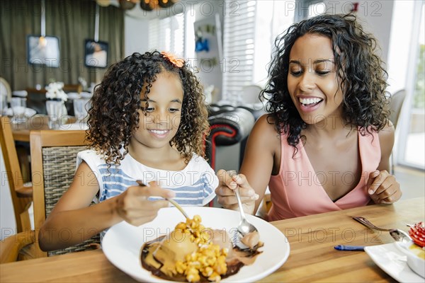 Mother and daughter sharing dessert in restaurant