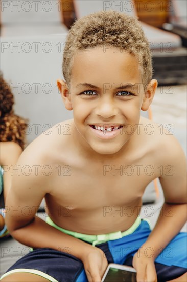 Mixed race boy holding cell phone on patio