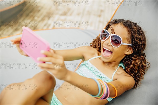 Mixed race girl taking selfie with cell phone on patio
