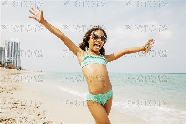 Mixed race girl cheering on beach