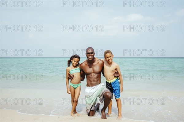 Father and children hugging on beach