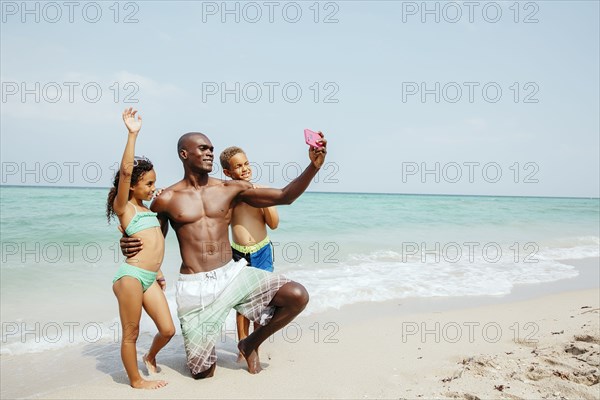 Father and children taking selfie on beach