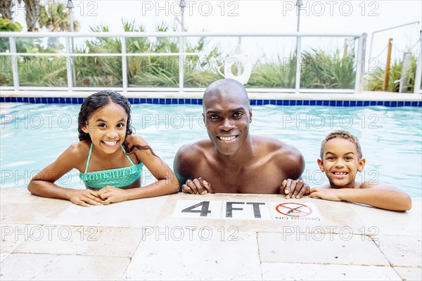 Father and children smiling in swimming pool