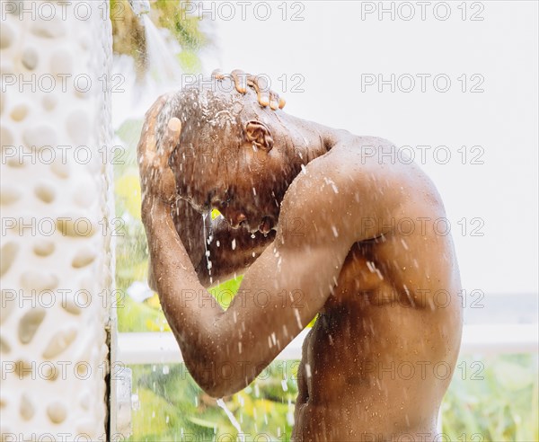 Black man rinsing off in outdoor shower