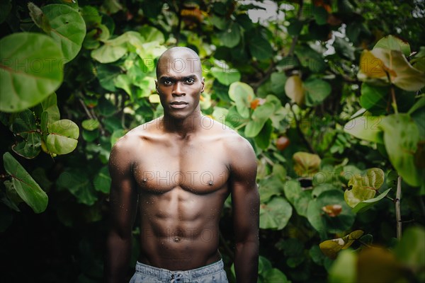 Black man standing in lush garden
