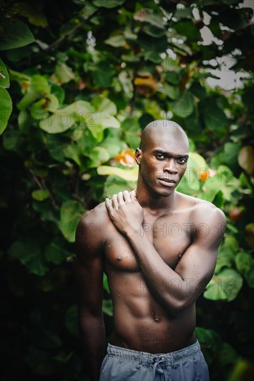 Black man standing in lush garden