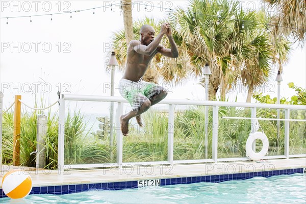 Black man jumping into swimming pool