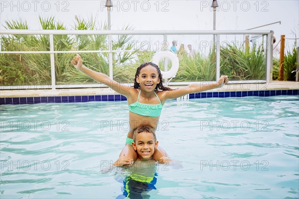 Mixed race children playing in swimming pool