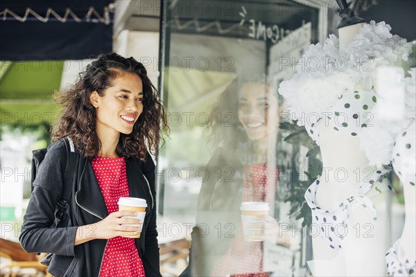 Mixed race woman window shopping outside store