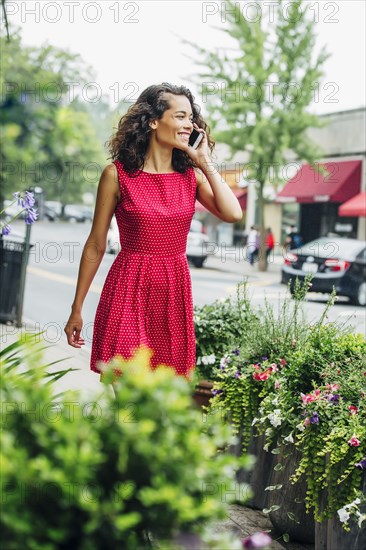 Mixed race woman talking on cell phone on city sidewalk