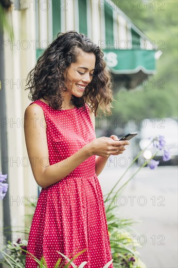 Mixed race woman using cell phone in city