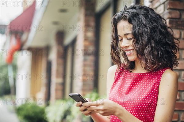 Mixed race woman using cell phone in city
