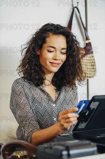 Mixed race clerk swiping credit card at register