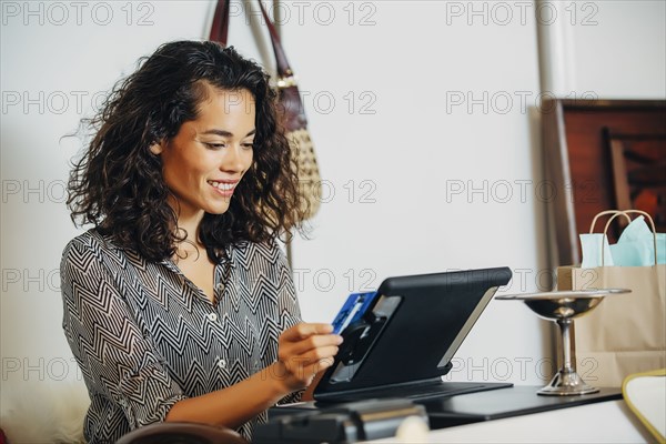 Mixed race clerk swiping credit card at register