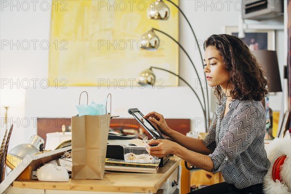 Mixed race clerk using register in shop