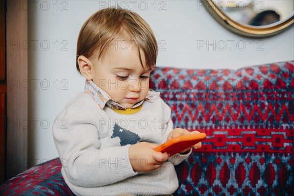 Caucasian baby boy using cell phone on sofa