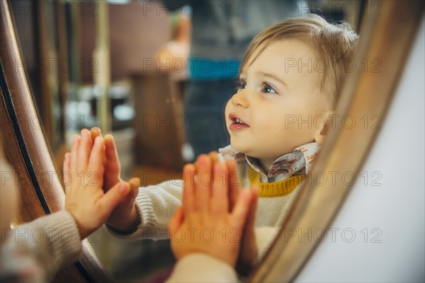 Caucasian baby boy standing at mirror