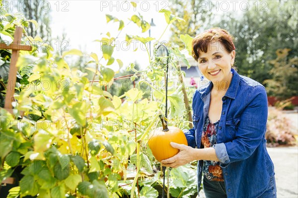 Caucasian woman holding pumpkin in garden