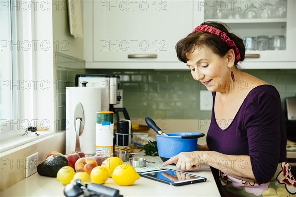 Caucasian woman using digital tablet in kitchen