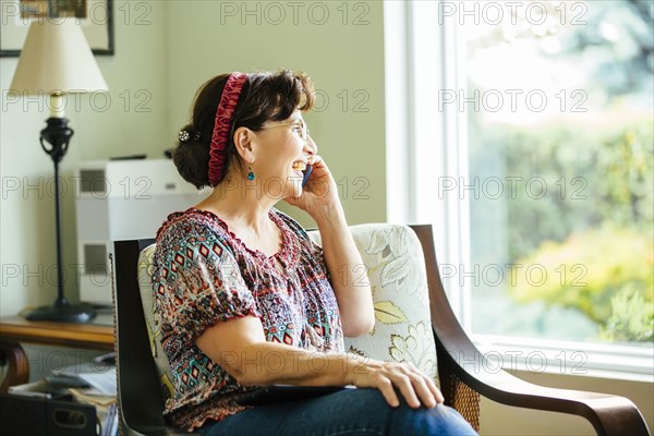 Caucasian woman talking on cell phone in armchair