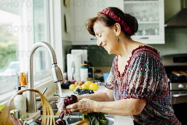 Caucasian woman washing vegetables in kitchen