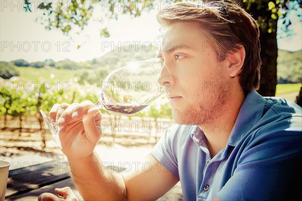 Caucasian man smelling wine in vineyard