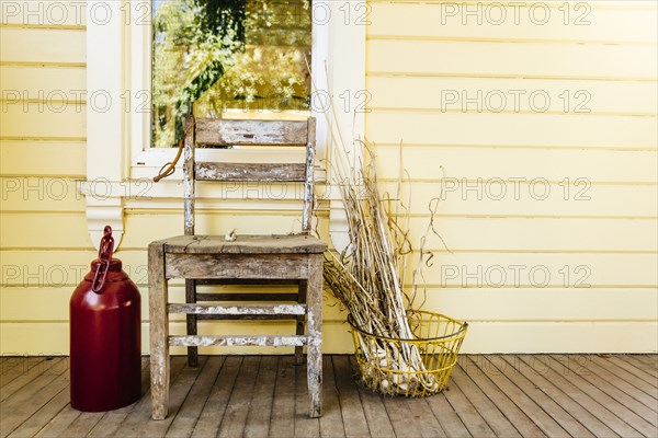 Chair with dried leaves and jug on porch