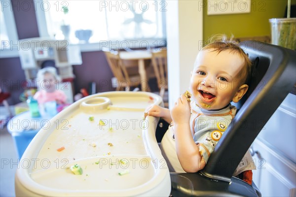 Caucasian boy eating in high chair