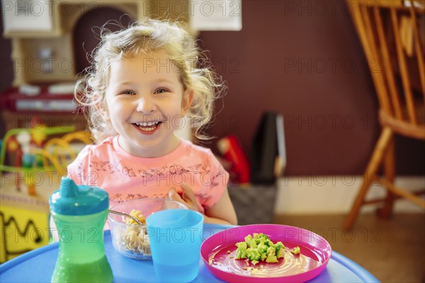 Caucasian girl eating in high chair