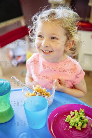 Caucasian girl eating in high chair