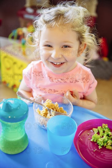 Caucasian girl eating in high chair