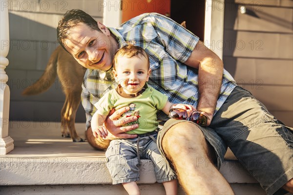 Caucasian father and son sitting on patio