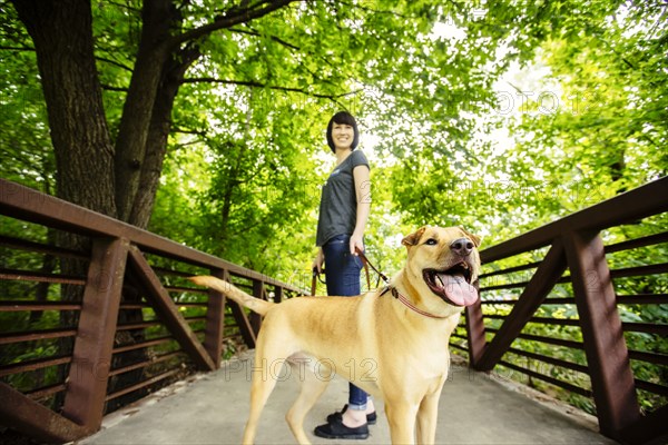 Caucasian woman walking dog on bridge