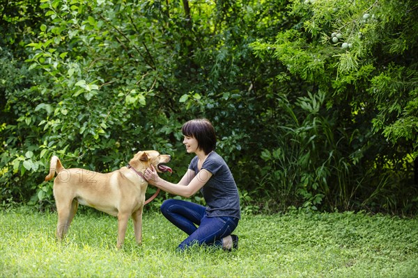 Caucasian woman petting dog in field