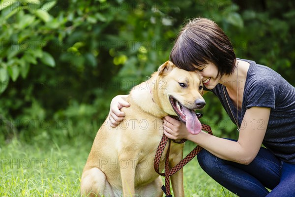 Caucasian woman petting dog in field