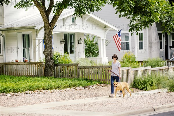 Caucasian woman walking dog in neighborhood