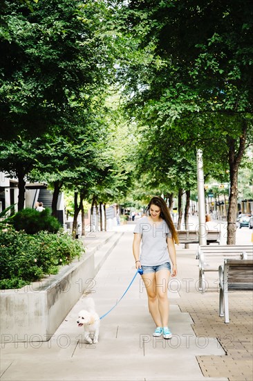 Caucasian woman walking dog in park