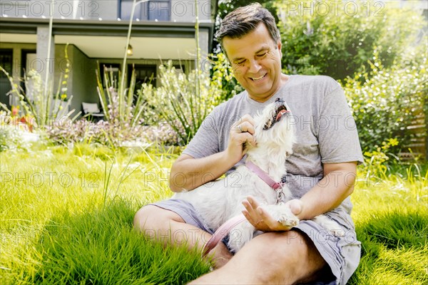 Caucasian man petting dog in grass