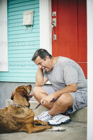 Caucasian man petting dog in front stoop