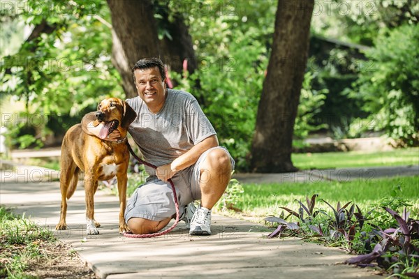 Caucasian man petting dog on sidewalk