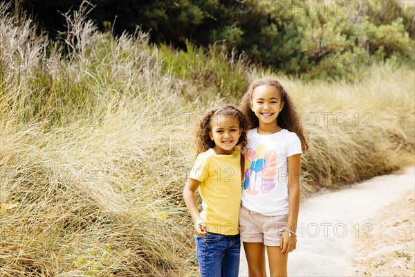 Mixed race sisters smiling on dirt path