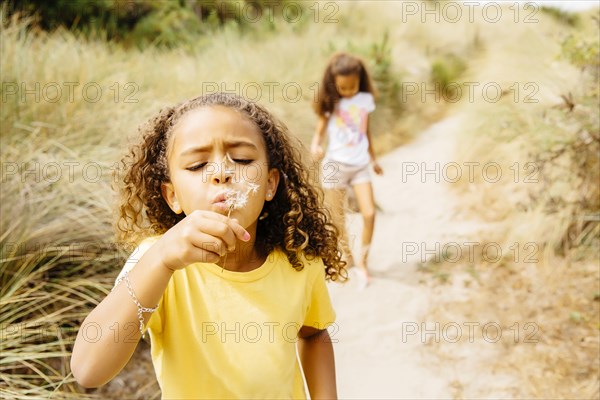 Mixed race girl blowing dandelion seeds