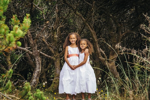 Mixed race sisters wearing dresses in garden