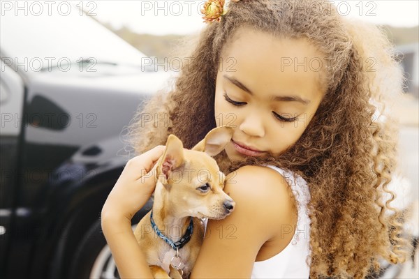 Mixed race girl petting dog outdoors