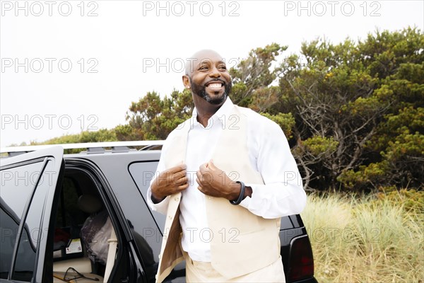 Well-dressed Black man outdoors near car
