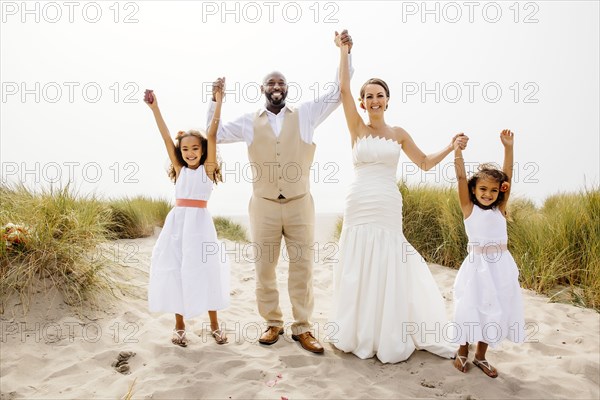Bride and groom cheering with flower girl daughters